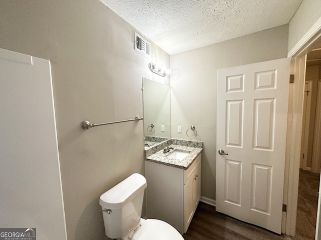 bathroom with vanity, wood-type flooring, a textured ceiling, and toilet