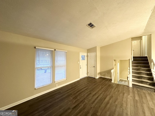 foyer entrance featuring dark hardwood / wood-style floors, vaulted ceiling, and a textured ceiling