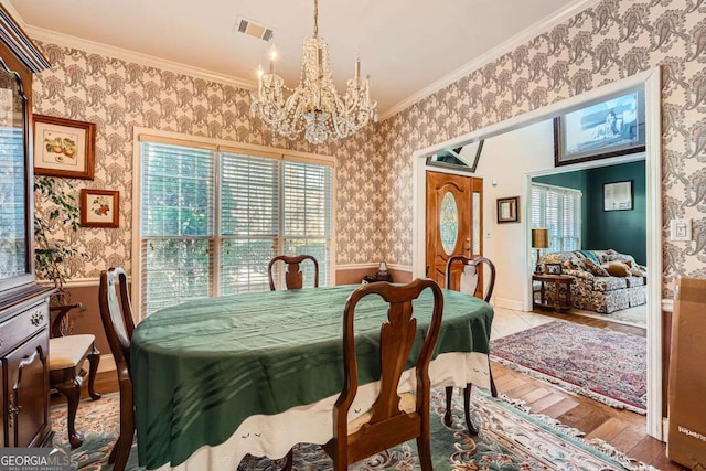 dining space featuring ornamental molding, light hardwood / wood-style flooring, and a notable chandelier