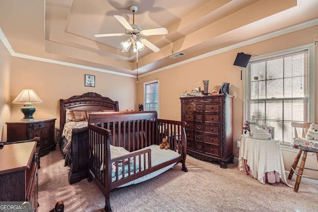 carpeted bedroom featuring multiple windows, crown molding, and a tray ceiling