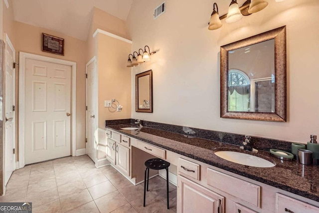 bathroom featuring tile patterned flooring, vanity, and vaulted ceiling