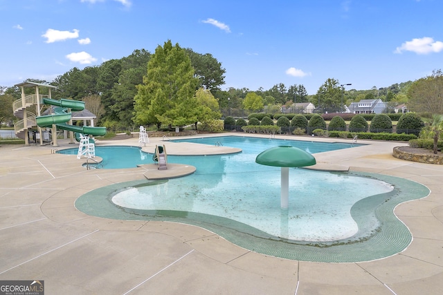 view of swimming pool featuring a water slide and a patio area