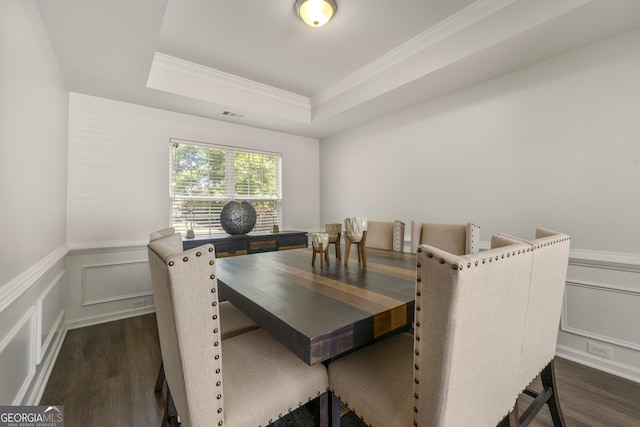 dining space with ornamental molding, dark hardwood / wood-style flooring, and a raised ceiling