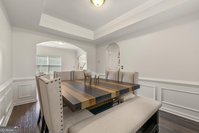 dining area with ornamental molding, dark hardwood / wood-style flooring, and a raised ceiling