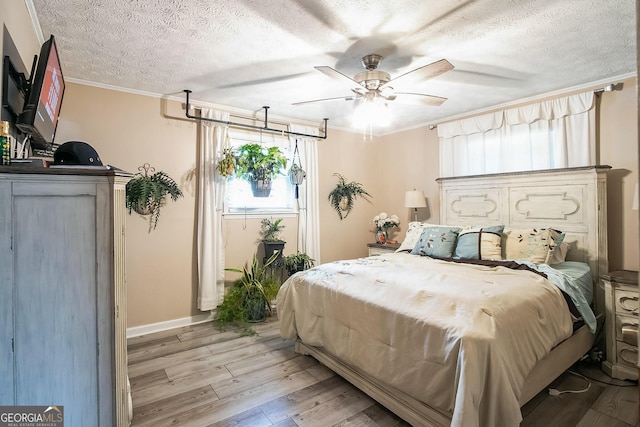 bedroom with crown molding, ceiling fan, a textured ceiling, and light wood-type flooring