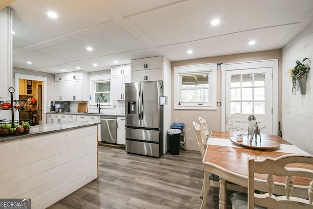 kitchen with light stone countertops, white cabinetry, appliances with stainless steel finishes, and light hardwood / wood-style flooring