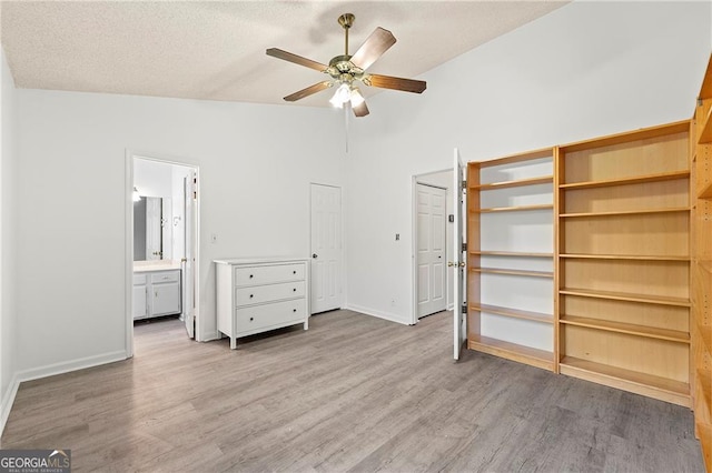 unfurnished bedroom featuring ensuite bath, ceiling fan, high vaulted ceiling, light hardwood / wood-style floors, and a textured ceiling