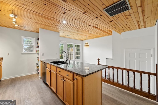 kitchen featuring sink, light wood-type flooring, dark stone countertops, dishwasher, and an island with sink