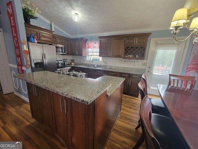 kitchen featuring stainless steel appliances, a kitchen island, dark wood-type flooring, and crown molding