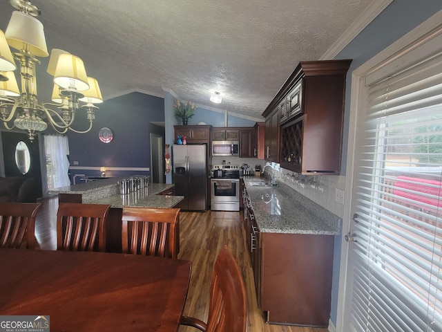 kitchen with dark wood-style flooring, ornamental molding, a sink, vaulted ceiling, and appliances with stainless steel finishes