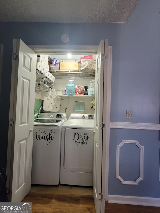 laundry room featuring laundry area, a textured ceiling, wood finished floors, and separate washer and dryer