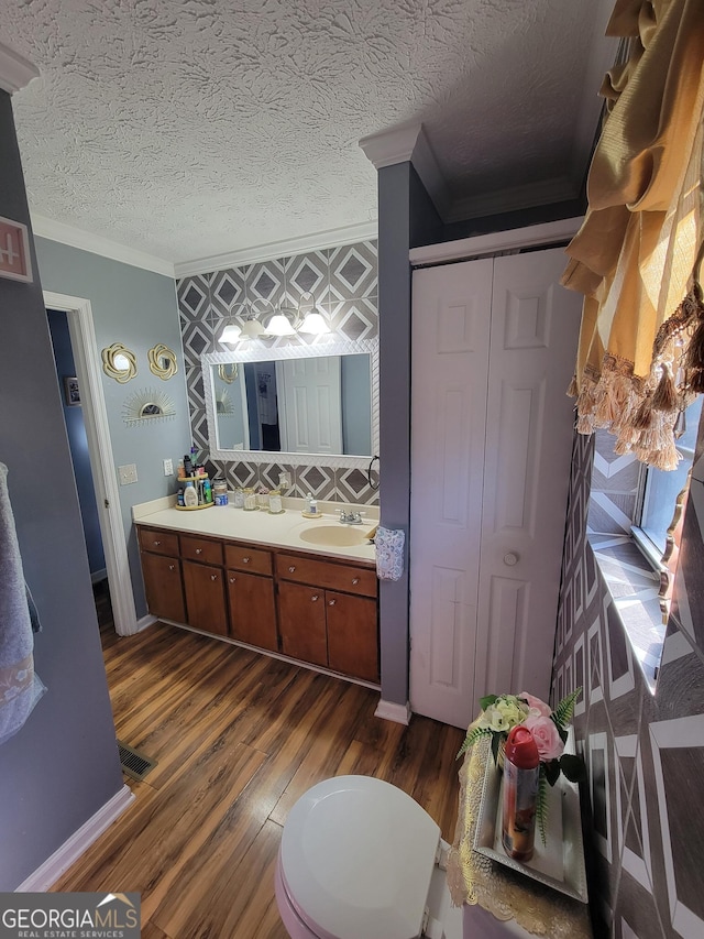 full bath featuring a sink, a textured ceiling, wood finished floors, and ornamental molding