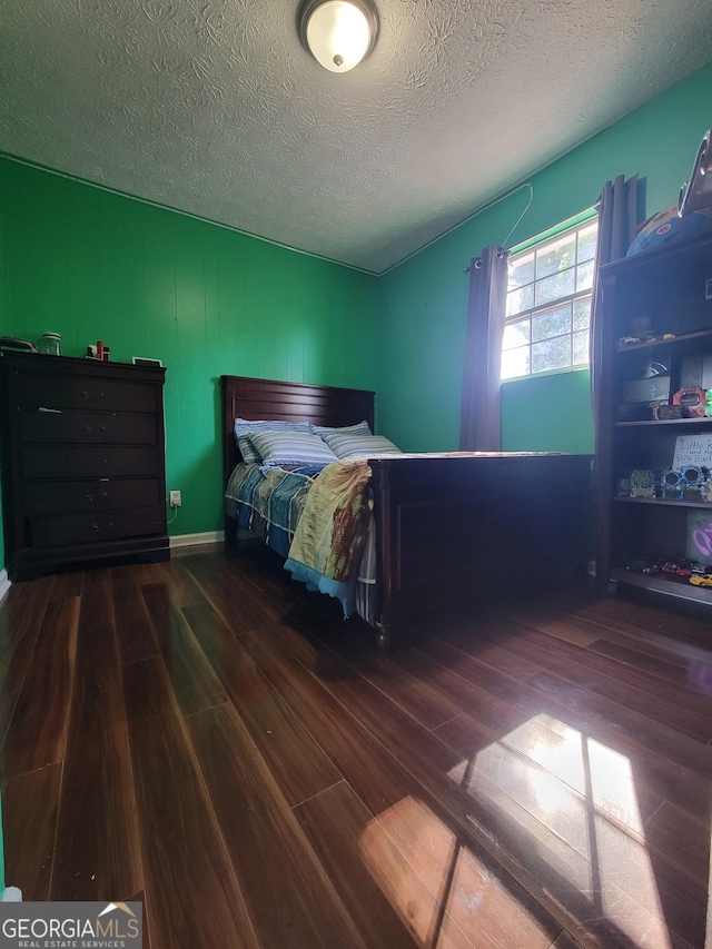 bedroom with a textured ceiling and wood finished floors