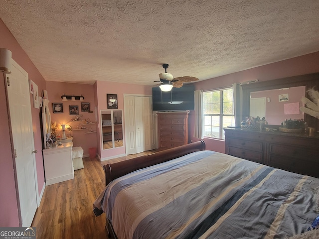 bedroom featuring wood finished floors, baseboards, ceiling fan, a closet, and a textured ceiling