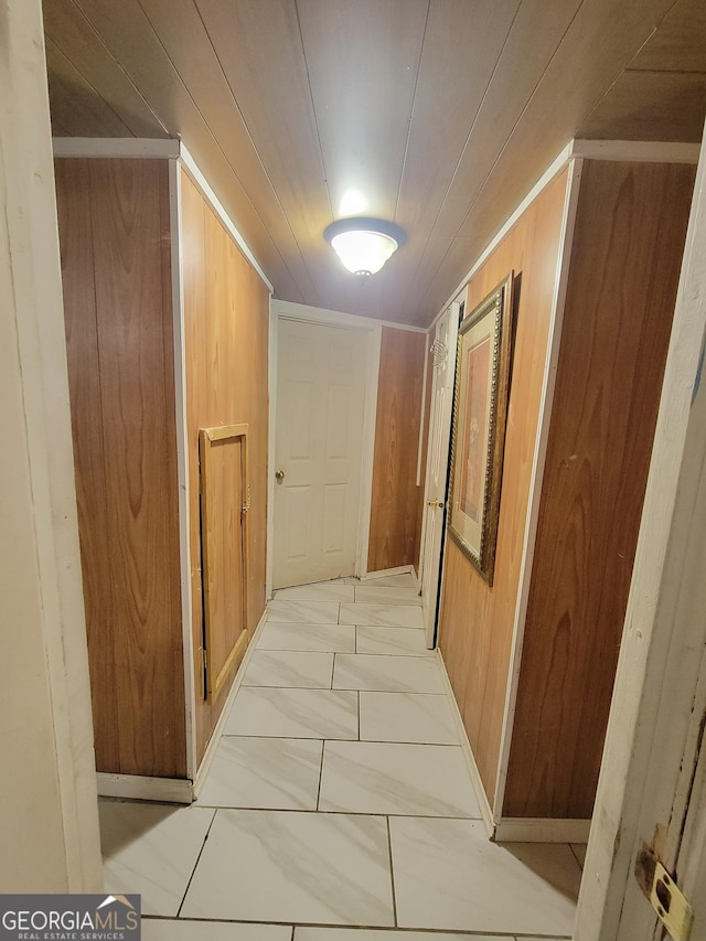 corridor featuring marble finish floor and wood walls