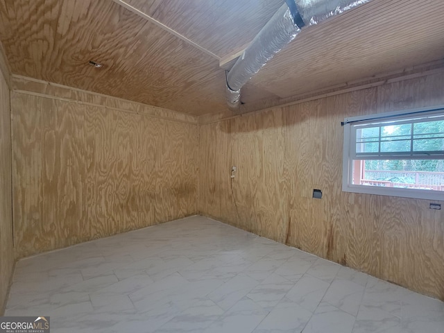 basement with wooden ceiling, marble finish floor, and wood walls