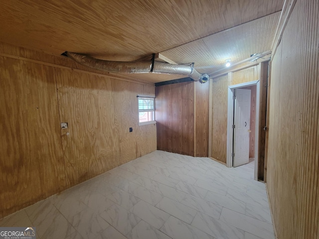 below grade area with wooden walls, marble finish floor, and wood ceiling