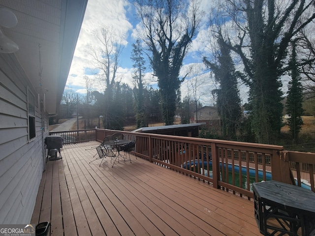 wooden terrace featuring a pool and outdoor dining area