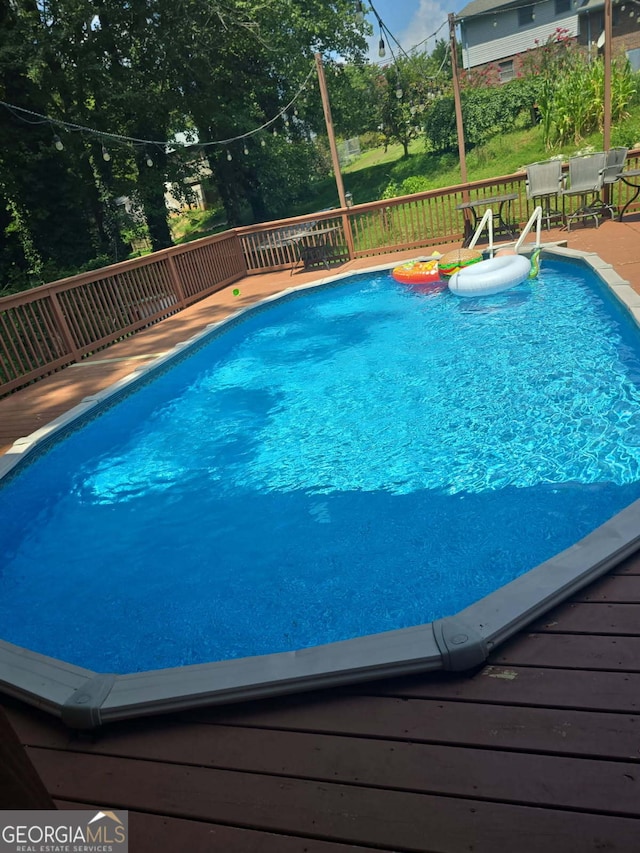 view of pool with outdoor dining space and a wooden deck