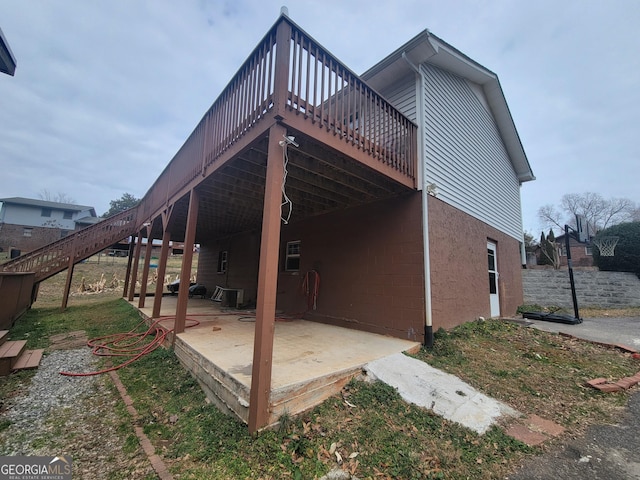 view of property exterior with a patio area, stairway, and a deck