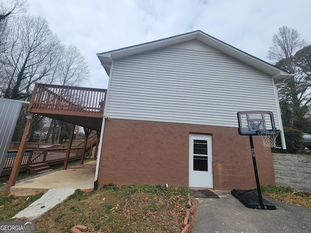 view of side of home with stucco siding, a deck, and a patio area