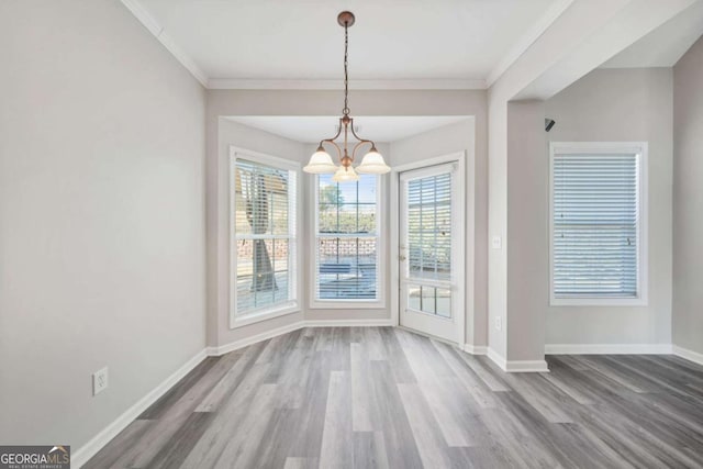 unfurnished dining area with ornamental molding, hardwood / wood-style floors, and an inviting chandelier