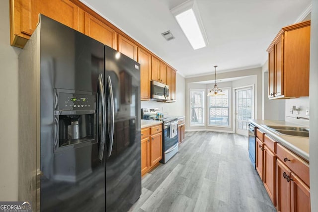 kitchen with sink, light hardwood / wood-style flooring, ornamental molding, pendant lighting, and stainless steel appliances