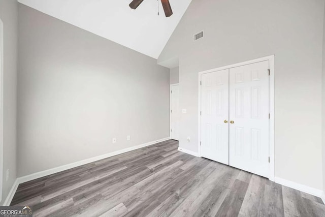 unfurnished bedroom featuring hardwood / wood-style flooring, high vaulted ceiling, a closet, and ceiling fan