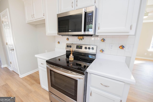 kitchen with appliances with stainless steel finishes, light wood-type flooring, white cabinets, and backsplash