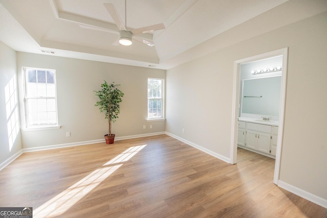 spare room with ceiling fan, a raised ceiling, sink, and light hardwood / wood-style flooring