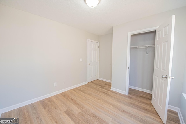 unfurnished bedroom with a textured ceiling, light hardwood / wood-style floors, and a closet