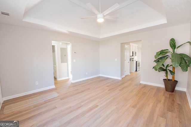 spare room with ceiling fan, light hardwood / wood-style floors, and a tray ceiling