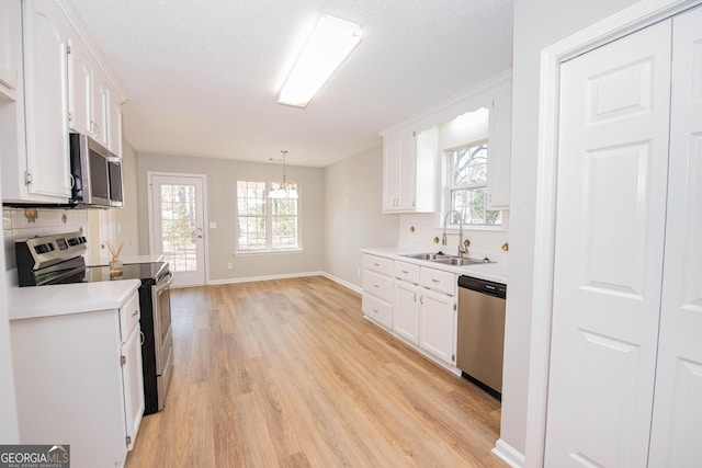 kitchen featuring pendant lighting, white cabinetry, stainless steel appliances, and sink