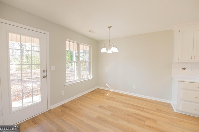 unfurnished dining area featuring a notable chandelier and light wood-type flooring