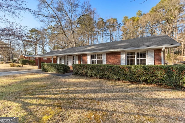 view of side of property featuring brick siding, a yard, and driveway