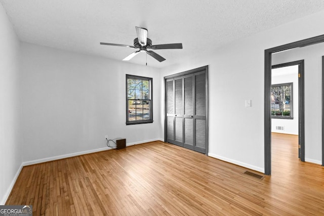 unfurnished bedroom with ceiling fan, light hardwood / wood-style flooring, a textured ceiling, and a closet