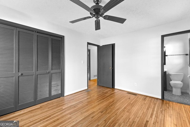 unfurnished bedroom featuring light hardwood / wood-style flooring, a closet, a textured ceiling, and ensuite bathroom