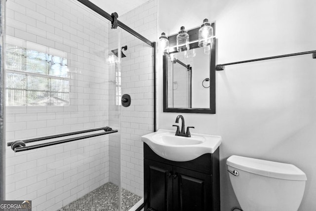 bathroom with a shower with door, vanity, and toilet