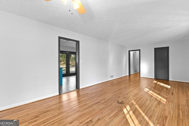 unfurnished room with ceiling fan, hardwood / wood-style flooring, french doors, and a textured ceiling