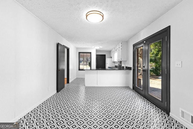 corridor with a textured ceiling and french doors