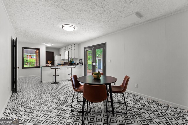 kitchen with a sink, baseboards, freestanding refrigerator, and white cabinetry