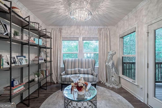 living area with dark wood-type flooring, a notable chandelier, ornamental molding, and a wealth of natural light