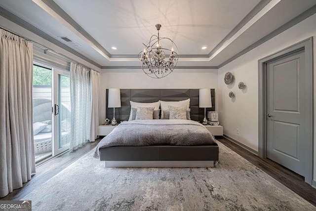 bedroom featuring access to exterior, a tray ceiling, a chandelier, and hardwood / wood-style flooring