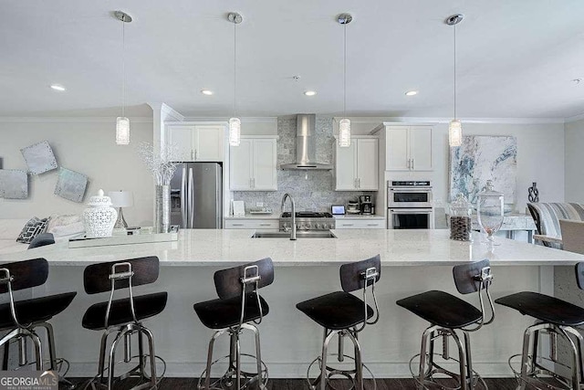 kitchen with sink, decorative light fixtures, stainless steel appliances, and wall chimney exhaust hood