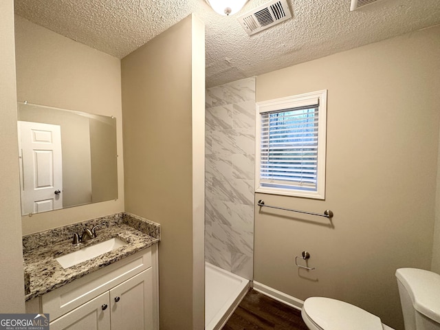 bathroom with hardwood / wood-style floors, a shower, vanity, toilet, and a textured ceiling