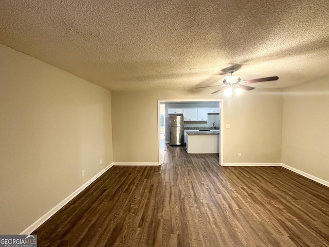 unfurnished living room with dark hardwood / wood-style floors, sink, a textured ceiling, and ceiling fan