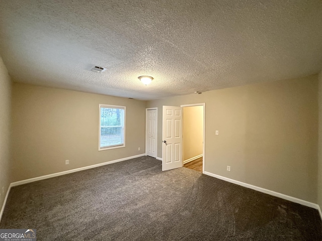 unfurnished bedroom with a textured ceiling, a closet, and dark colored carpet