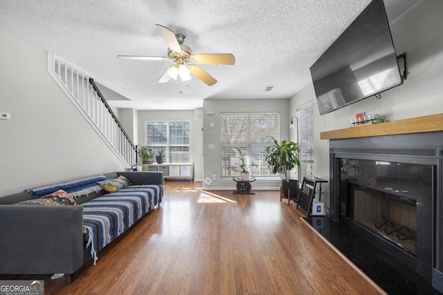 living room featuring ceiling fan, hardwood / wood-style flooring, and a textured ceiling