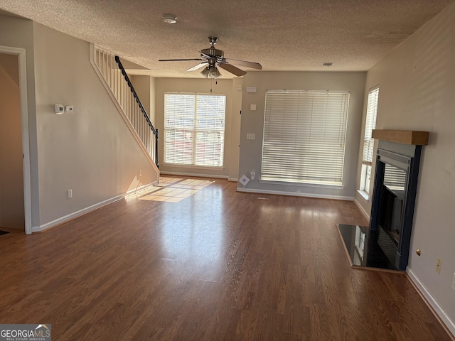 unfurnished living room featuring ceiling fan, dark hardwood / wood-style floors, and a textured ceiling