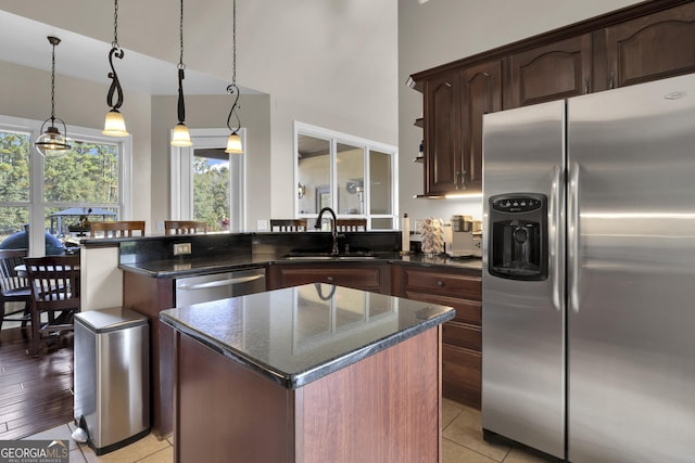 kitchen featuring a kitchen island, appliances with stainless steel finishes, sink, dark stone countertops, and dark brown cabinetry